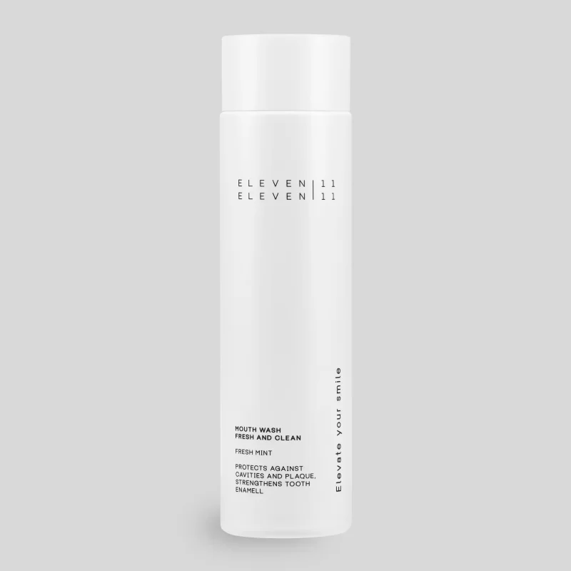 Eine wei&szlig;e Flasche der ELEVEN ELEVEN Mundsp&uuml;lung steht freigestellt vor grauem Hintergrund. Die minimalistische Verpackung tr&auml;gt den Schriftzug &bdquo;Mouth Wash &ndash; Fresh and Clean&ldquo; sowie den Slogan &bdquo;Elevate your smile&ldquo;.